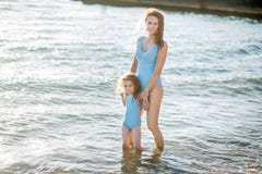 Piękni potomstwa matka i córka ma zabawę odpoczywa na morzu Stoją w wodzie w ten sam uśmiechu i swimsuit obraz royalty free Piękni potomstwa matka i córka ma zabawę odpoczywa na morzu Stoją w wodzie w ten sam uśmiechu i swimsuit obraz royalty free