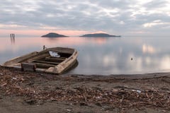 Piękny widok Trasimeno jeziorny Umbria przy półmrokiem, z troszkę, stara łódź stronniczo wypełniał wodą, doskonale wciąż obraz stock Piękny widok Trasimeno jeziorny Umbria przy półmrokiem, z troszkę, stara łódź stronniczo wypełniał wodą, doskonale wciąż obraz stock