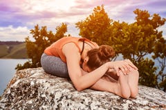 Plan rapproché de jeune femme faisant l'exercice de yoga sur la pierre contre le paysage image libre de droits Plan rapproché de jeune femme faisant l'exercice de yoga sur la pierre contre le paysage image libre de droits