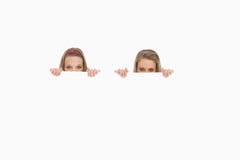 Plan rapproché de jeunes femmes se cachant derrière un signe blanc image stock Plan rapproché de jeunes femmes se cachant derrière un signe blanc image stock