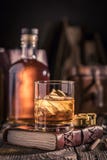 Plan rapproché de verre de whiskey avec de la glace et la bouteille d'or photographie stock libre de droits Plan rapproché de verre de whiskey avec de la glace et la bouteille d'or photographie stock libre de droits