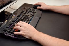 Plan rapproché des mains masculines sur un clavier noir de jeu avec la lampe au néon sur une table noire Vue de côté images libres de droits Plan rapproché des mains masculines sur un clavier noir de jeu avec la lampe au néon sur une table noire Vue de côté images libres de droits
