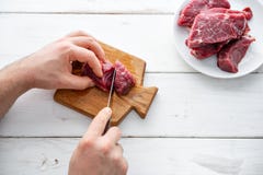 Plan rapproché des mains des tranches d'une coupe de boucher de viande crue outre d'une grande échine Viande crue Bifteck de boeu photo libre de droits Plan rapproché des mains des tranches d'une coupe de boucher de viande crue outre d'une grande échine Viande crue Bifteck de boeu photo libre de droits