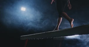 Plan rapproché du pied d'une fille professionnelle de gymnaste sautant dans le mouvement lent dans la fumée sur une poutre d'équi clips vidéos Plan rapproché du pied d'une fille professionnelle de gymnaste sautant dans le mouvement lent dans la fumée sur une poutre d'équi clips vidéos
