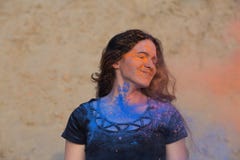 Plan rapproché tiré de la femme heureuse de brune avec de longs cheveux bouclés couverts de peinture sèche colorée Holi au désert photos stock Plan rapproché tiré de la femme heureuse de brune avec de longs cheveux bouclés couverts de peinture sèche colorée Holi au désert photos stock