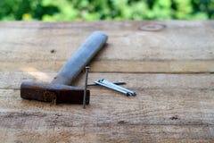Planche en bois avec une position de clou près d'un marteau rouillé et d'une pile des clous au foyer sur un fond brouillé de natu images libres de droits Planche en bois avec une position de clou près d'un marteau rouillé et d'une pile des clous au foyer sur un fond brouillé de natu images libres de droits
