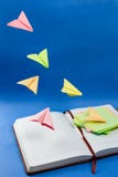 Planes made from colorful note papers flying over the notebook. royalty free stock image Planes made from colorful note papers flying over the notebook. royalty free stock image