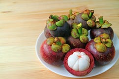Plate of Ripe Purple Mangosteen Whole Fruits and Opened to Show Delectable Pure White Meat on the Wooden Table royalty free stock photos Plate of Ripe Purple Mangosteen Whole Fruits and Opened to Show Delectable Pure White Meat on the Wooden Table royalty free stock photos