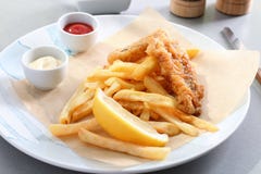 Plate with tasty fried fish, chips and sauces on table Royalty Free Stock Photos Plate with tasty fried fish, chips and sauces on table Royalty Free Stock Photos