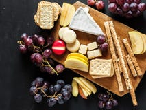 Plateau de fromage sur la planche à découper avec des morceaux de pomme fraîche et grains sur un fond noir de tableau photographie stock Plateau de fromage sur la planche à découper avec des morceaux de pomme fraîche et grains sur un fond noir de tableau photographie stock