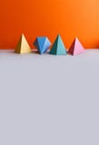 Platonic solid geometric figures. Three-dimensional pyramid rectangular triangle objects on orange gray background royalty free stock photos Platonic solid geometric figures. Three-dimensional pyramid rectangular triangle objects on orange gray background royalty free stock photos