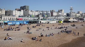 Playa de Brighton ocupada con los turistas y los visitantes el festivo en la opinión hermosa de la cacerola del tiempo Playa de Brighton ocupada con los turistas y los visitantes el festivo en la opinión hermosa de la cacerola del tiempo