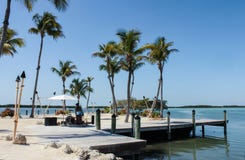 Playa de Tiki empleada un muelle rodeado con los tourches del tiki con un músico del reggae que juega debajo de las palmeras imagen de archivo libre de regalías Playa de Tiki empleada un muelle rodeado con los tourches del tiki con un músico del reggae que juega debajo de las palmeras imagen de archivo libre de regalías