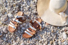 Plażowych otoczaków rzemiennych sandałów i słomianego kapeluszu wakacje zdjęcie stock Plażowych otoczaków rzemiennych sandałów i słomianego kapeluszu wakacje zdjęcie stock