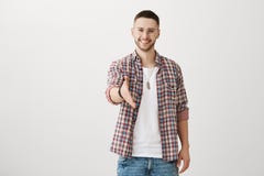 Pleased to meet such person like you. Handsome unshaven male student in eyewear pulling hand towards camera, giving firm stock photography Pleased to meet such person like you. Handsome unshaven male student in eyewear pulling hand towards camera, giving firm stock photography