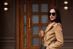 Plenerowy portret młoda atrakcyjna elegancka kobieta jest ubranym stosownych akcesoria, beżowy modny żakiet, trzyma papierową fil obrazy stock Plenerowy portret młoda atrakcyjna elegancka kobieta jest ubranym stosownych akcesoria, beżowy modny żakiet, trzyma papierową fil obrazy stock