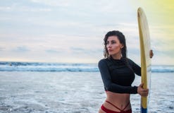 Plenerowy strzał młoda dziewczyna wosków surfboard dla bezpiecznych jazd fal, ubierający w czarnym swimsuit, bierze opiekę bezpie zdjęcia stock Plenerowy strzał młoda dziewczyna wosków surfboard dla bezpiecznych jazd fal, ubierający w czarnym swimsuit, bierze opiekę bezpie zdjęcia stock