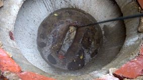 Plumber cleans clogged pipes in outside.