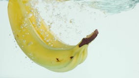 Plátanos que hunden en el agua en el fondo blanco en la cámara lenta imágenes de archivo libres de regalías Plátanos que hunden en el agua en el fondo blanco en la cámara lenta imágenes de archivo libres de regalías