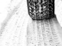 Pneus de voiture dans la neige sur la bande de roulement luisante glaciale de route images stock Pneus de voiture dans la neige sur la bande de roulement luisante glaciale de route images stock