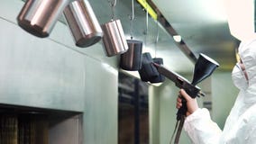 Poederdeklaag van metaaldelen Een mens in een beschermende kostuumnevels poedert verf van een kanon op metaalproducten stock videobeelden Poederdeklaag van metaaldelen Een mens in een beschermende kostuumnevels poedert verf van een kanon op metaalproducten stock videobeelden