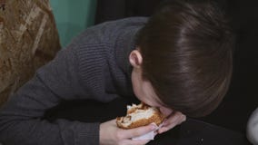 Pojke som ?ter en hamburgare i en restaurang Pojken rymmer en hamburgare med n?tk?tt arkivfilmer Pojke som ?ter en hamburgare i en restaurang Pojken rymmer en hamburgare med n?tk?tt arkivfilmer