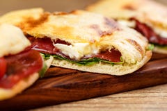 Pokrojony pizzy calzone whith baleron na drewnianej desce obraz royalty free Pokrojony pizzy calzone whith baleron na drewnianej desce obraz royalty free