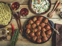 Polpette casalinghe in salsa al pomodoro Padella su una superficie di legno, riso con le verdure, pasta immagine stock libera da diritti Polpette casalinghe in salsa al pomodoro Padella su una superficie di legno, riso con le verdure, pasta immagine stock libera da diritti