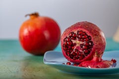 Pomegranate and red seeds of fruit on a blue plate. Beautiful bright tropical fruit on a green table. stock photos Pomegranate and red seeds of fruit on a blue plate. Beautiful bright tropical fruit on a green table. stock photos