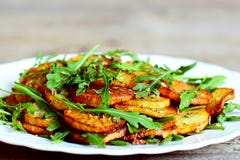 Pommes de terre épicées avec l'arugula d'un plat Les pommes de terre rôties avec l'arugula frais et l'assaisonnement sec simple s photos stock Pommes de terre épicées avec l'arugula d'un plat Les pommes de terre rôties avec l'arugula frais et l'assaisonnement sec simple s photos stock