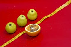 Pommes et orange qu'une mesure attachent du ruban adhésif sur un fond rouge images libres de droits Pommes et orange qu'une mesure attachent du ruban adhésif sur un fond rouge images libres de droits
