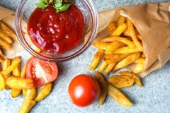 Pommes frites, pommes de terre frites avec le ketchup et tomates sur le fond du granit gris-bleu photos libres de droits Pommes frites, pommes de terre frites avec le ketchup et tomates sur le fond du granit gris-bleu photos libres de droits