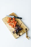 Pomodori ciliegia e basilico su un tagliere di legno Vista superiore, fondo bianco fotografia stock Pomodori ciliegia e basilico su un tagliere di legno Vista superiore, fondo bianco fotografia stock
