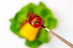 Pomodoro in un cucchiaio su un fondo delle verdure variopinte vaghe immagini stock libere da diritti Pomodoro in un cucchiaio su un fondo delle verdure variopinte vaghe immagini stock libere da diritti