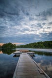 Pont en bois de pied menant à une plate-forme avec un banc sur un lac calme en Suède photo libre de droits Pont en bois de pied menant à une plate-forme avec un banc sur un lac calme en Suède photo libre de droits