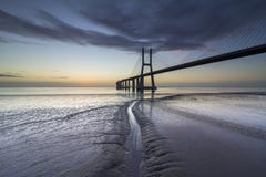 Ponte lungo sopra il Tago a Lisbona all'alba fotografia stock Ponte lungo sopra il Tago a Lisbona all'alba fotografia stock