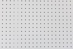 Ponto em ordem ou fileiras e colunas dos furos na parede branca do pegboard fotografia de stock royalty free Ponto em ordem ou fileiras e colunas dos furos na parede branca do pegboard fotografia de stock royalty free