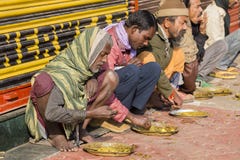 Poor indian people eating free food at the street in Varanasi, India