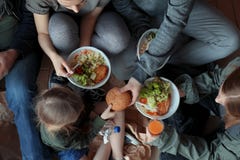 Poor people with plates of food sitting on floor stock photography Poor people with plates of food sitting on floor stock photography