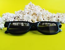 Popcorn and 3d glasses on yellow background. Concept pastime, entertainment and cinema stock image Popcorn and 3d glasses on yellow background. Concept pastime, entertainment and cinema stock image