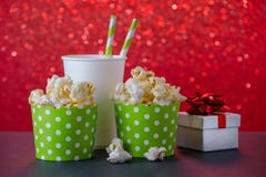 Popcorn och drink i den pappers- koppen för filmen och underhållning, en gåva, röd bokehbakgrund arkivfoto Popcorn och drink i den pappers- koppen för filmen och underhållning, en gåva, röd bokehbakgrund arkivfoto