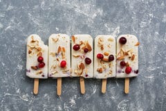 Popsicles мороженого клюквы в ряд на серой предпосылке со свежими ягодами и гайками Взгляд сверху, плоское положение стоковое изображение rf Popsicles мороженого клюквы в ряд на серой предпосылке со свежими ягодами и гайками Взгляд сверху, плоское положение стоковое изображение rf