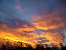 Por do sol com as nuvens impetuosas douradas no verão imagem de stock Por do sol com as nuvens impetuosas douradas no verão imagem de stock