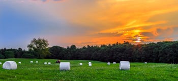 Por do sol no prado com Hay Bales imagens de stock royalty free Por do sol no prado com Hay Bales imagens de stock royalty free