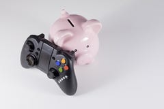 Porcellino salvadanaio con il regolatore del gioco Immagini Stock Porcellino salvadanaio con il regolatore del gioco Immagini Stock