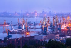 Port commercial de mer la nuit contre l'usine sidérurgique fonctionnante Images stock Port commercial de mer la nuit contre l'usine sidérurgique fonctionnante Images stock