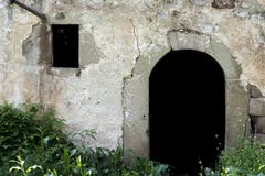 Porta velha da pedra da entrada e janela pequena na floresta imagem de stock Porta velha da pedra da entrada e janela pequena na floresta imagem de stock