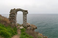 A porta velha do arco de Bulgária da fortaleza de Kaliakra através das virgens joga-se na legenda do mar imagem de stock royalty free A porta velha do arco de Bulgária da fortaleza de Kaliakra através das virgens joga-se na legenda do mar imagem de stock royalty free