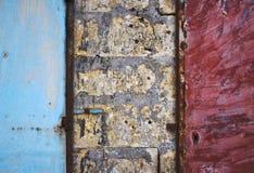 Portas pintadas azuis e vermelhas do metal em um tijolo e em uma parede áspera concreta que formam um fundo abstrato sujo da text foto de stock royalty free Portas pintadas azuis e vermelhas do metal em um tijolo e em uma parede áspera concreta que formam um fundo abstrato sujo da text foto de stock royalty free