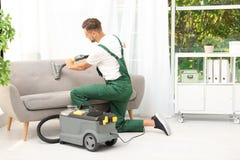 Portiere maschio che rimuove sporcizia dal sofà fotografia stock Portiere maschio che rimuove sporcizia dal sofà fotografia stock